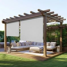 an outdoor living area with couches, table and pergolated patio cover on the grass