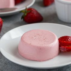 two pieces of cake on a plate with strawberries in the back ground and other plates behind it