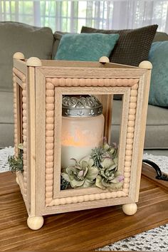 a candle in a wooden frame with succulents