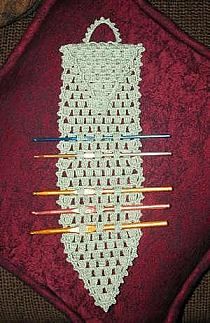 an old crocheted tie with knitting needles in it