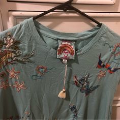 This Johnny Was T-Shirt Is Perfect For Any Occasion, Whether You're Going Out For A Casual Day Or A Night Out, This Top Is A Great Choice. The Shirt Is Made Of 100% Cotton And Features A Crew Neckline, Puff Short Sleeves, And Beautiful Bird Flower Ufo Embroidery Accents. Bohemian Short Sleeve Tops For Loungewear, Spring Bohemian Loungewear Tops, Casual Sleeveless T-shirt For Loungewear, Bohemian Cotton Tops For Loungewear, Blue T-shirt For Spring Loungewear, Blue Bohemian Tops For Loungewear, Bohemian Blue Tops For Loungewear, Bohemian Blue Top For Loungewear, Beautiful Bird