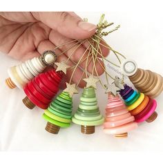 a hand holding a bunch of colorful wooden christmas tree ornament ornaments in different colors