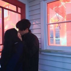 a man and woman kissing in front of a window with the sun shining through it