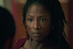 a woman with dreadlocks stares into the camera while standing in front of a mirror