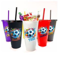 three different colored cups with straws and candy in them on a white table top