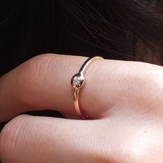 a close up of a person's hand wearing a gold ring with a diamond