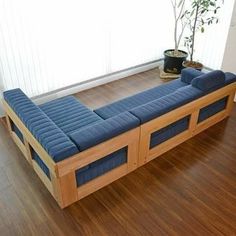 a blue couch sitting on top of a wooden floor next to a potted plant