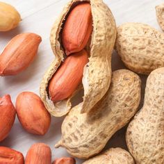 peanuts and cashews on a white surface with one nut still in the shell