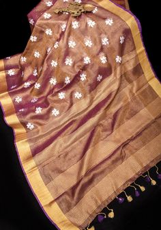 Presenting a peppy tissue Linen saree in Purple with a gold Zari border. The Saree has beautiful Parijat floral embroidery and comes with a matching blouse piece. Pretty tassels and silver zari adorn the pallu.  Please note that this is 100 % pure linen tissue and there is no cotton mix.  Color of Saree: Pink with gold tissue  Saree may appear to slightly vary in shading based on light and screen settings. None of the pics are edited for color.   Comes with Fall and edging (Pico) Gold Dupatta With Resham Embroidery In Cotton Silk, Gold Dupatta With Resham Embroidery In Slub Silk, Gold Slub Silk Dupatta With Resham Embroidery, Gold Pre-draped Saree With Resham Embroidery For Puja, Gold Handloom Dola Silk Pre-draped Saree, Diwali Resham Embroidered Slub Silk Saree, Diwali Cotton Silk Saree With Resham Embroidery, Resham Embroidered Slub Silk Saree For Diwali, Slub Silk Saree With Resham Embroidery For Diwali