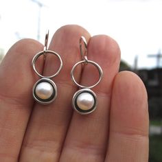 A minimal and modern look with a nod to old school pearl earrings. These sterling silver and pearl earrings are set in a modern round shadow bezel style and hang from sculptural open circles. The cultured pearl is half drilled on the bottom and glued to a sterling post soldered to the necklace for durability. You will get a lot of compliments when wearing this mini art piece.To see all my pearl jewelry go here:https://www.etsy.com/shop/marmarModern?ref=seller-platform-mcnav&section_id=132837 Modern Round Sterling Silver Pearl Earrings, Modern Hypoallergenic Pearl Earrings For Everyday, Modern Round Pearl Earrings, Modern Dangle Pearl Earrings For Everyday, Modern Everyday Dangle Pearl Earrings, Modern Silver Pierced Pearl Earrings, Modern Sterling Silver Pearl Earrings For Pierced Ears, Modern Sterling Silver Pearl Earrings For Gift, Modern Sterling Silver Pearl Earrings