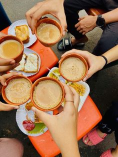 several people are holding cups with drinks in them