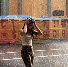 a woman standing in the rain with her hands on her head