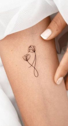 a woman's thigh with a small flower tattoo on her left side ribcage