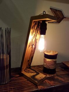 a lamp that is sitting on top of a table next to a cup and some sticks