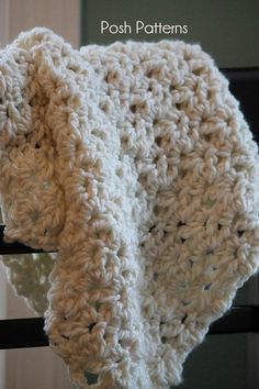 a white crocheted blanket hanging from a hook on a black rail with the words posh patterns written below it