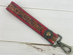 a red and brown leather key foble on a white wooden surface