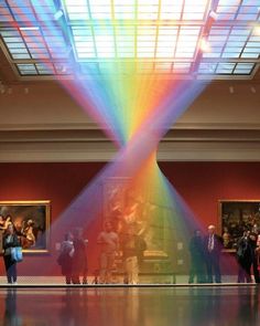 a group of people standing under a rainbow colored skylight