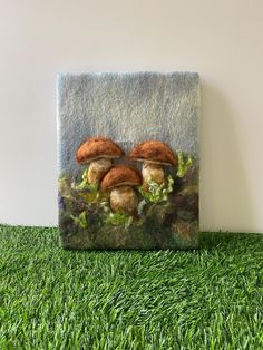 two mushrooms sitting on top of green grass next to a white wall in the shape of a square