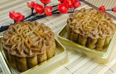 two cakes sitting on top of metal pans covered in frosting next to red flowers