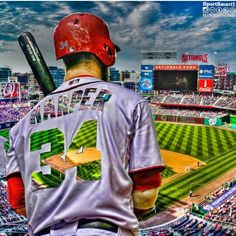 a baseball player holding a bat in front of a stadium filled with people and fans