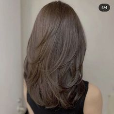 the back of a woman's head with long, brown hair in front of a mirror