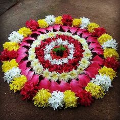 a colorful flower arrangement on the ground with white and yellow flowers in it's center