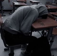 a person sleeping on top of a desk in a classroom