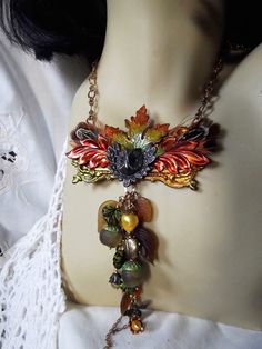 a close up of a mannequin's torso wearing a necklace with leaves and beads