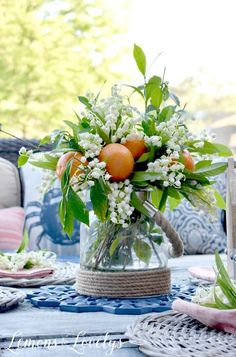 a vase filled with oranges and white flowers on top of a blue table cloth