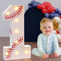 a baby sitting in front of a baseball themed number one