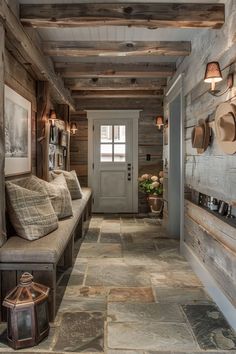 a hallway with wooden walls and flooring has two benches on either side of the door