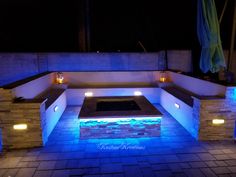 an outdoor hot tub lit up at night with blue lights on the walls and floor