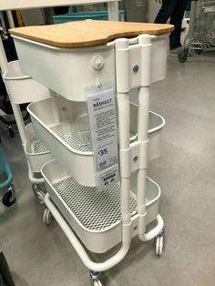 a kitchen cart with a wooden cutting board on it's top and two wheels