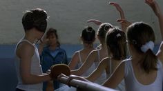 several girls in ballet clothes are holding their hands up