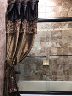 a bath tub sitting under a window next to a tiled shower stall in a bathroom