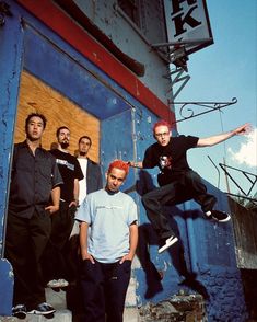 a group of young men standing next to each other in front of a blue building