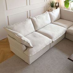 a large white couch sitting on top of a hard wood floor next to a window