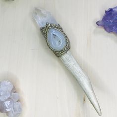 an animal's tooth with a stone in the center on a table next to crystals