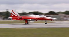 a red and white jet taking off from an airport runway