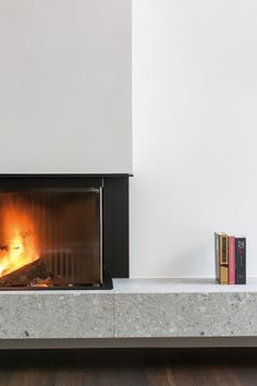 a fire place with a book on the side and a white wall behind it in a living room