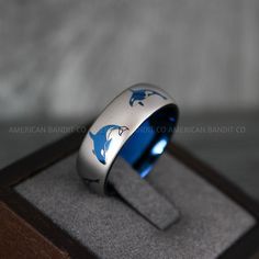 a ring with dolphins painted on it sitting in a box