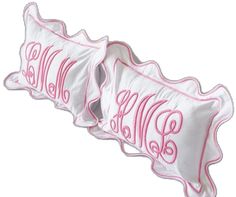 three white pillows with pink monogrammed letters on the front and back of them