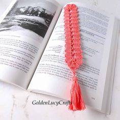 an open book with a tassel on top of it next to a red crochet tassel