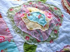 a close up view of a quilted table cloth with flowers and leaves on it