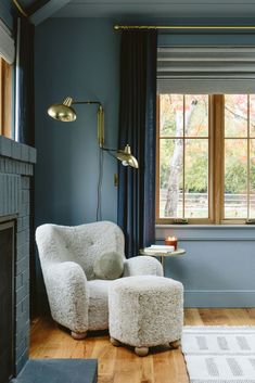 a chair and ottoman in front of a window with blue walls, wooden floors and wood flooring