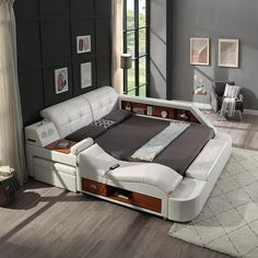 a white leather bed with drawers and headboard in a living room next to a large window