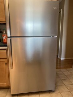 a stainless steel refrigerator in a kitchen with tile flooring