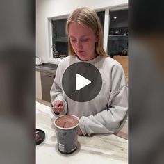 a woman sitting at a table in front of a cup