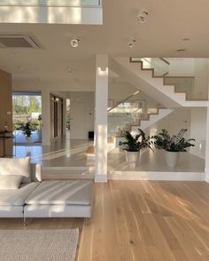 a living room filled with white furniture and wooden flooring next to a stair case