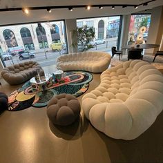 a living room filled with lots of furniture and large windows overlooking the city street in front of it